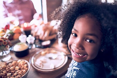 Little girl looking back and smiling at thanksgiving table