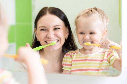 mother and child brushing their teeth together